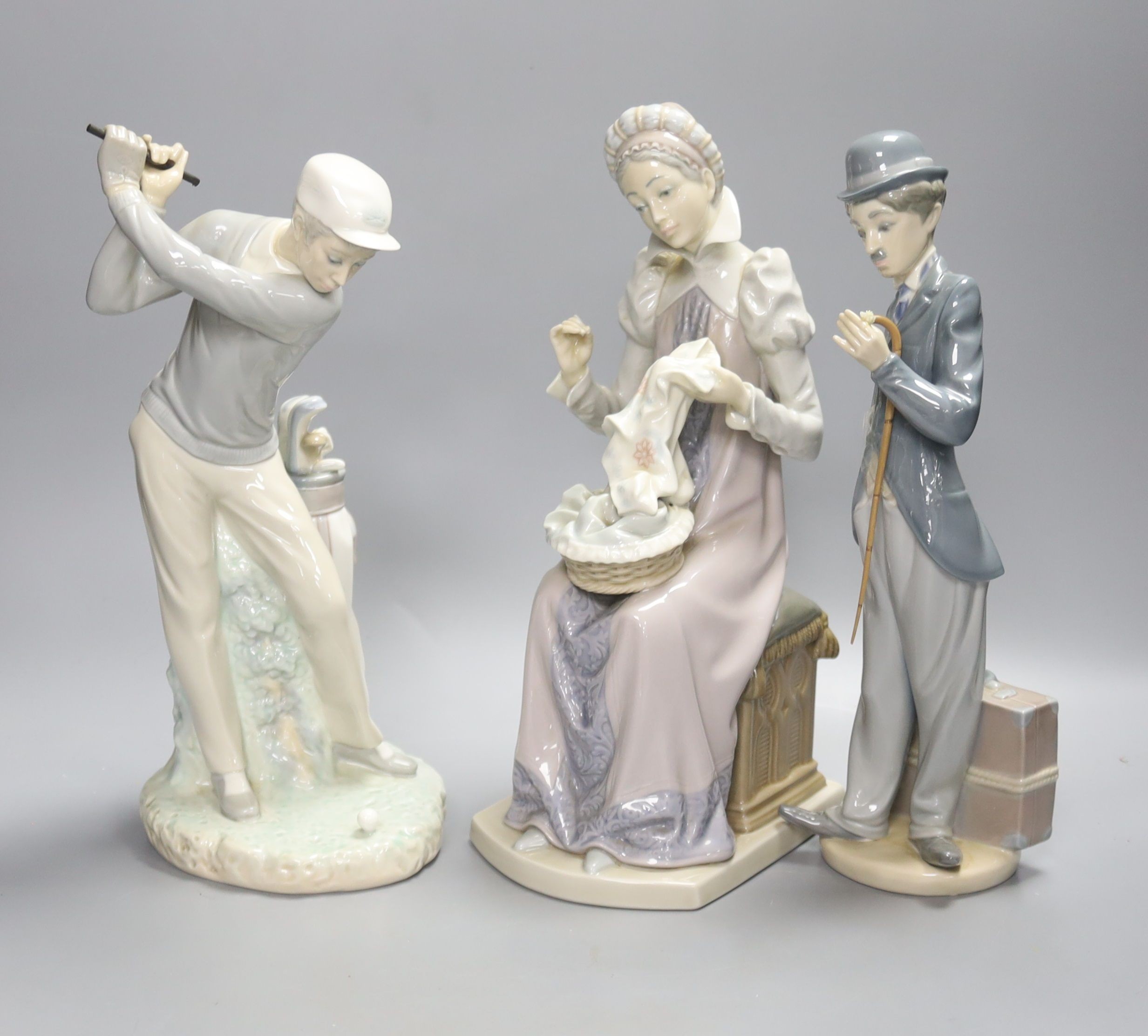 Three Lladro figures: a golfer, Charlie Chaplin and a lady sewing, tallest 28cm